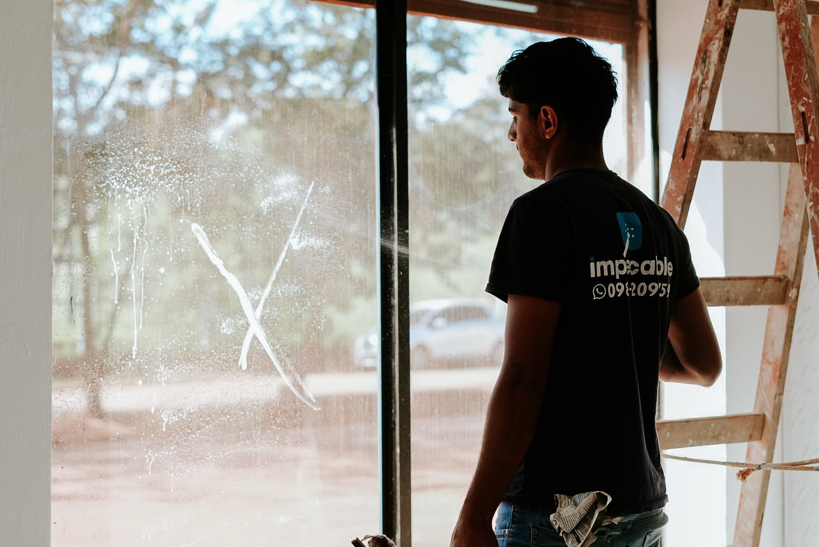 Profesional de Impecable realizando limpieza de ventanas con equipamiento especializado